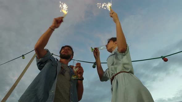 Under view of couple having fun waving with firework candles