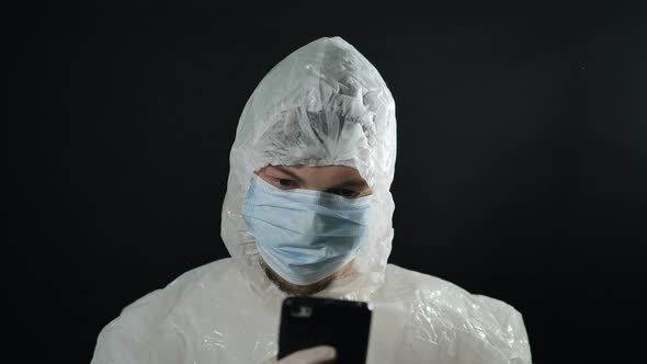 Man in White Suit and Medical Mask, Puts on Foil Cap To Protect Against Radiation From 5G Towers