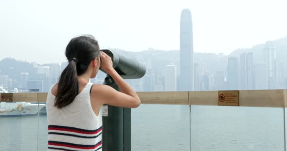 Woman tourist looking though binocular in Hong Kong  