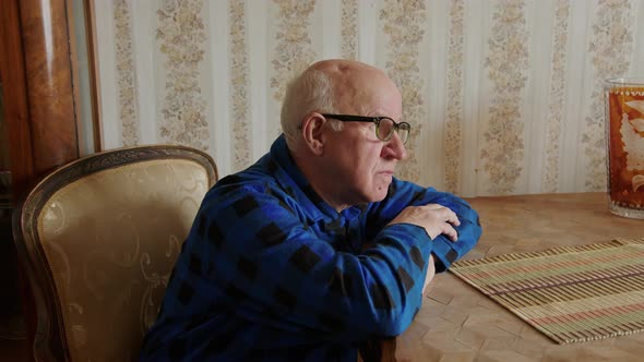 Senior Man Looking Out the Window Leaning on the Table