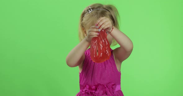 Child Having Fun Making Red Slime. Kid Playing with Hand Made Toy Slime
