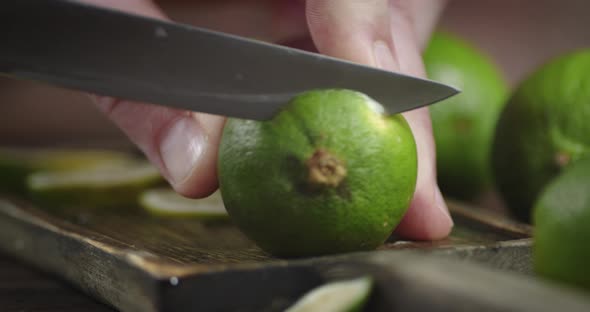 Hands Men Cut Off a Piece of Juicy Lime on a Cutting Board. 