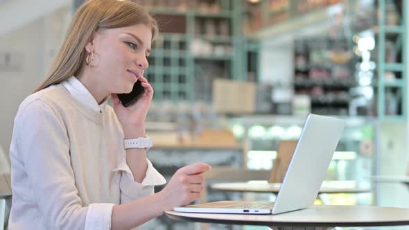 Young Woman Talking on Smartphone in Cafe