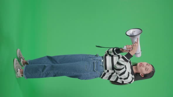 Full Body Side View Of An Asian Woman Speaking On Megaphone In The Green Screen Studio