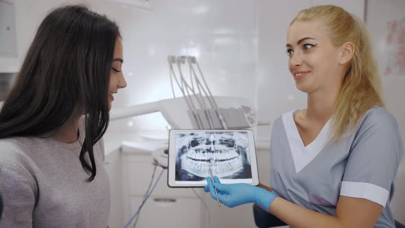 Dentist and Patient Choosing Treatment in a Consultation with Medical Equipment in the Background