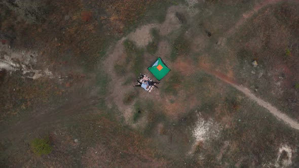 Overhead View of Young Family Lies on Blanket Near Tent and Enjoys Camp Vacation Together