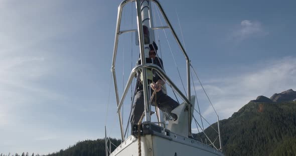 Slow Motion of Male at Bow of Sailing Boat Pulling Rope and Chain With Anchor on Sunny Day at Alaska