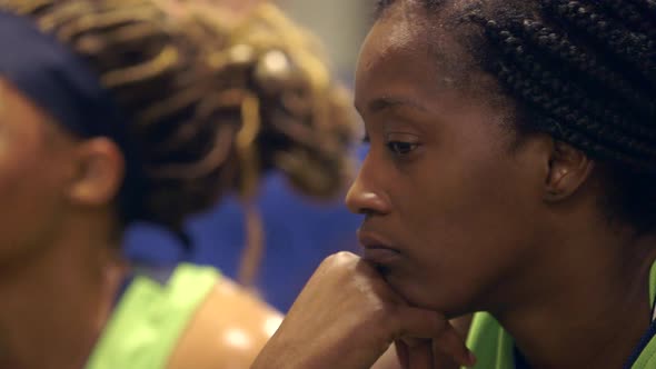 An African American female basketball player listens to a pep talk in the locker room between halves