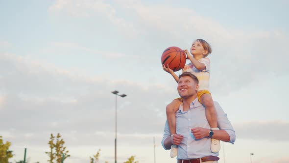 Little boy with dad playing basketball outdoors