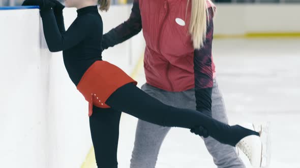 Trainer explaining figure skater how to hold her leg right