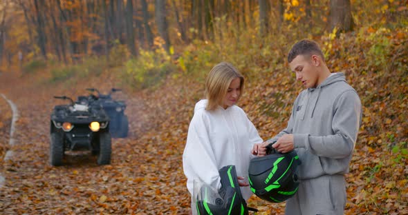 A Young Couple Putting on Helmets in the Autumn Forest