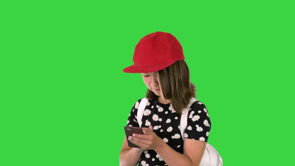 Young Girl Wearing a Backpack and Using Smartphone on a Green Screen Chroma Key