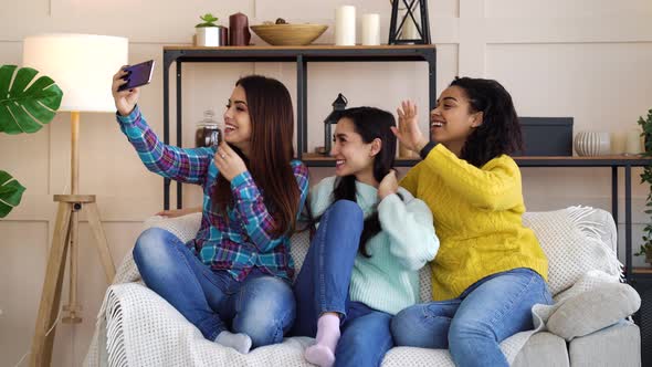 Cheerful girls sitting at home and live streaming using smartphone