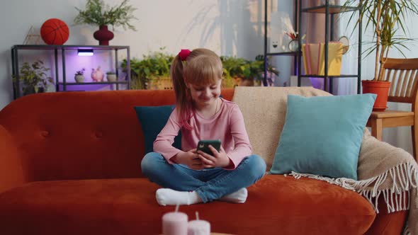 Child Toddler Hold Smartphone Watching Funny Cartoons Chatting with Friends on Couch Alone at Home