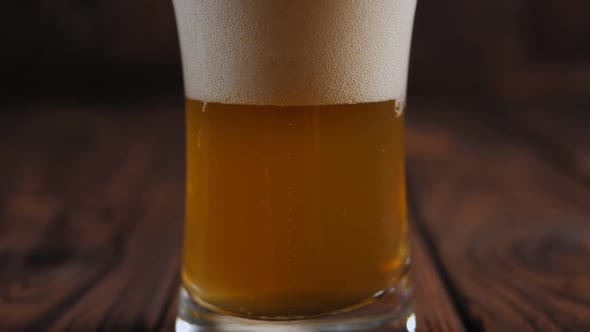 Closeup of a Glass of Beer with Lots of Foam and Bubbles on a Wooden Background
