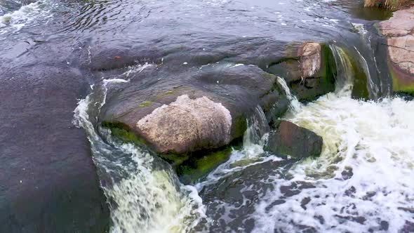 A fast stream among smooth dark and wet stones