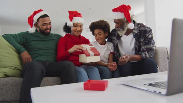 Multi-generation family opening gift box while having video chat on his laptop