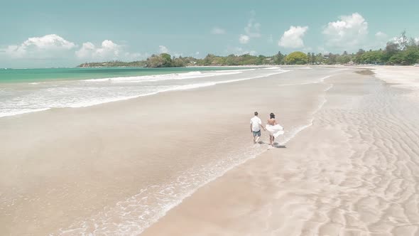 Couple Walking On A Sandy White Tropical Beach