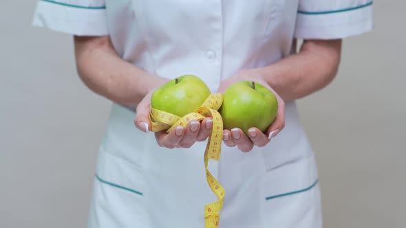 Nutritionist Doctor Healthy Lifestyle Concept - Holding Two Organic Green Apples and Measuring Tape