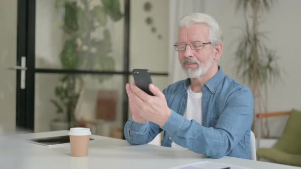 Attractive Senior Old Man Using Smartphone in Office