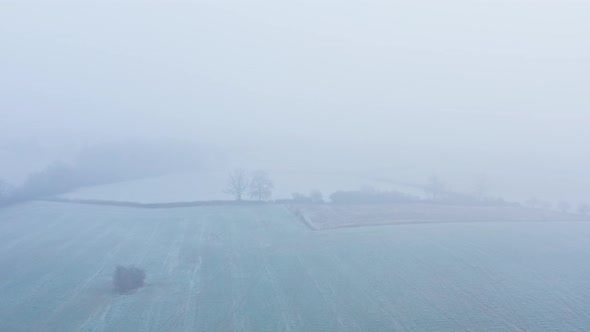 Aerial drone video of countryside and fields in misty foggy weather conditions, rural English scene 