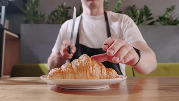 Baker Cuts Fresh Crispy Croissant and Shows the Chocolate Filling Close Up