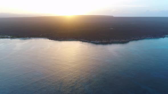 Eagles bay seen from ocean, sunset in background. Aerial backward