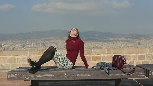 Female Sunbathing on a Bench at Top Point of City
