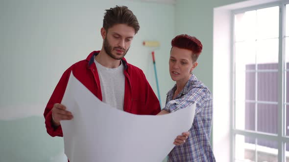 Slim Confident Caucasian Woman Talking with Man Examining Blueprint Pointing Away Leaving