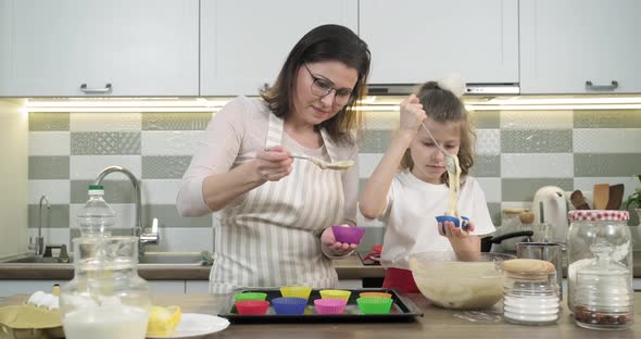 Mother and Daughter Child 9, 10 Years Old Preparing Cupcakes Together at Home in Kitchen