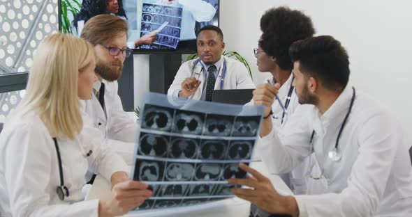 Doctors Advising about the Treatment of Patient Using X-ray Scan During Meeting in Office Room