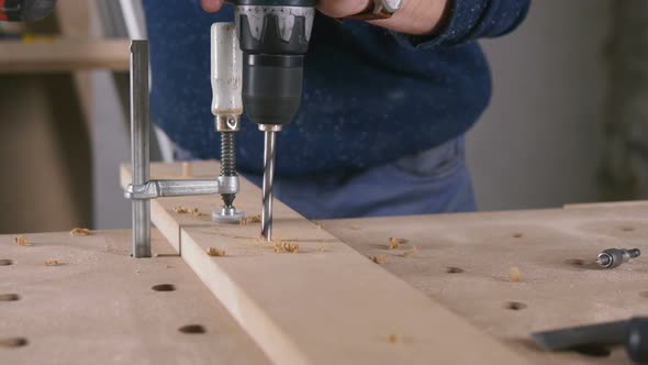 Young Man Piercing a Hole Through a Wooden Plank