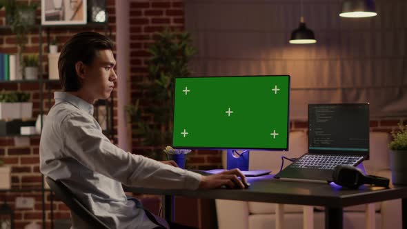 Asian Businessman Looking at Computer with Greenscreen