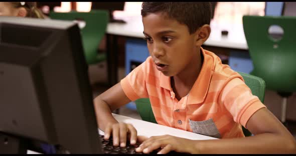 Schoolboy studying on personal computer in classroom
