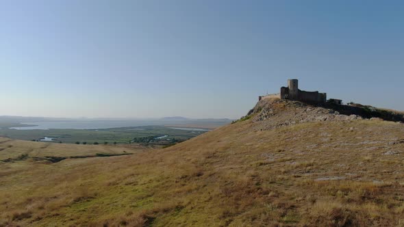 Aerial drone rising shot with front side of Enisala, medieval fortress on top of a hill surrounded b