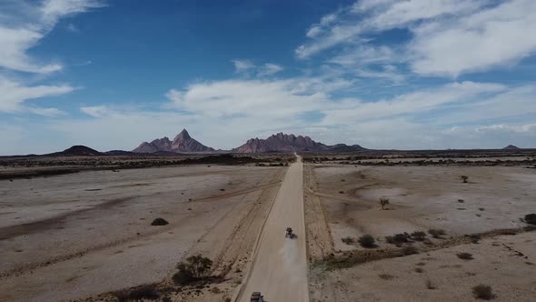 Aerial view on a long dusty road across the desert to the mountains, Namibia