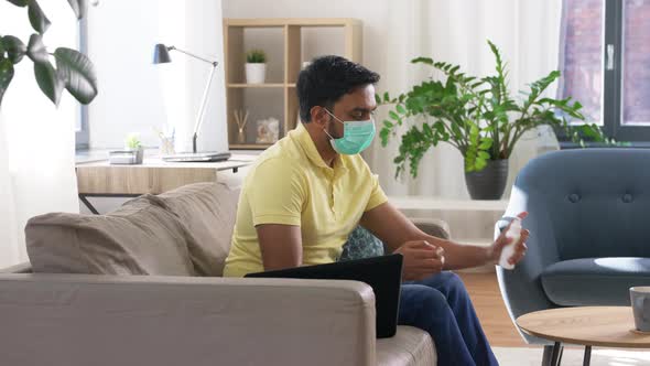 Man in Mask Using Hand Sanitizer at Home Office