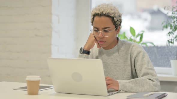 African Woman Feeling Worried While Working on Laptop in Office