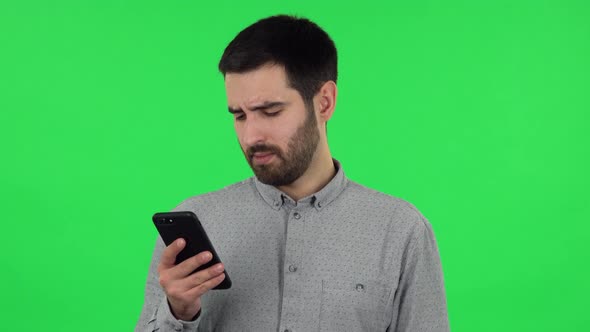 Portrait of Brunette Guy Is Texting on His Phone and Upset. Green Screen