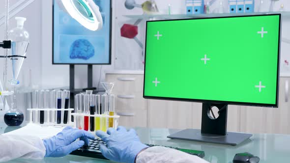 Chemist in Protective Gloves Works on Computer with Green Screen