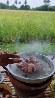Young Women Grilling Thai Pork Barbecue on Pan in the Hut Along with a View Over the Rice Fields