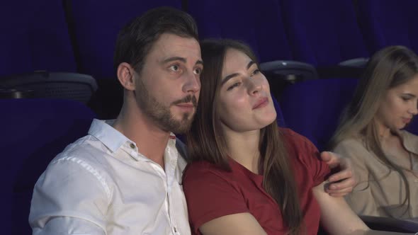 Cute Boy and Girl Are Sitting in an Embrace in the Cinema