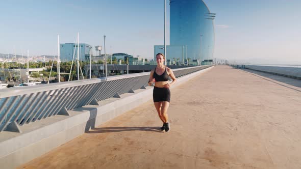 Sportswoman Running on Embankment in Morning