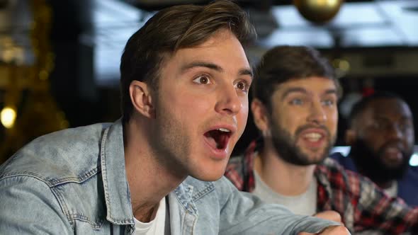 Emotional Male Fans Cheering for Favorite Sports Team Victory, Evening in Pub