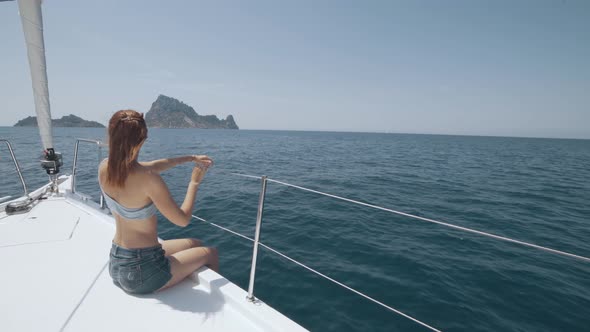 Beautiful Woman on a Yacht Enjoys the Journey on the Background of the Islands of Ibiza or Mallorca