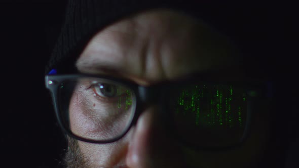 Bearded Hacker in Eyeglasses Working on Computer in the Night Green Programming Code Reflecting on