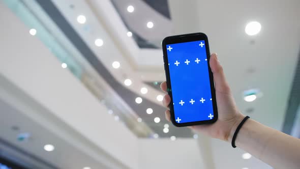 A Phone in a Woman's Hand in Front of a Shopping Mall