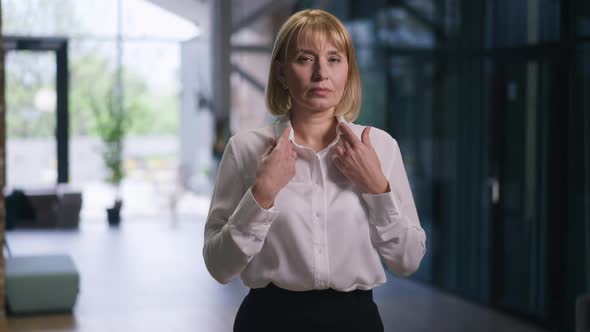 Confident Adult Businesswoman Crossing Hands Looking at Camera Standing in Office Hall Indoors