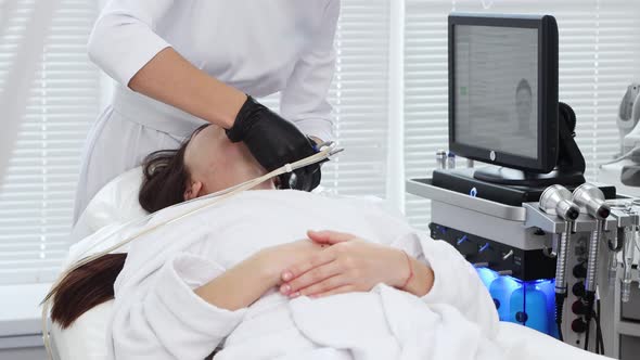 Face Massage  Young Woman Lying on a Couch and Having an Electric Massage Procedure on Her Neck