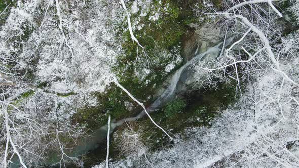 Stream of Water Flowing Among the White Rocks in the Forest in Winter